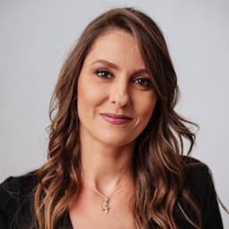 Marina Proença, mentora de carreira e liderança, sorrindo de braços cruzados.